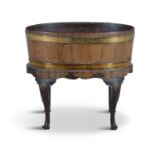 A GEORGE III MAHOGANY OVAL OPEN WINE COOLER, raised on a stand with shell carved legs and trifid