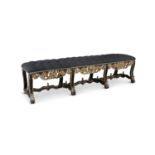 AN ITALIAN EBONSIED AND GILT LONG STOOL, 19th century, covered in grey buttoned upholstery, with