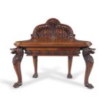 A 19TH CENTURY IRISH WALNUT SIDE TABLE, the arched backboard heavily carved with geometric bands and