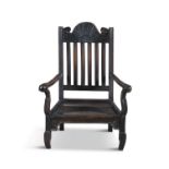 A JACOBEAN STAINED OAK LOW ELBOW CHAIR, the stick back with fan crest rail above a solid seat, on