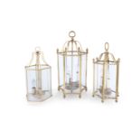 THREE BRASS FRAMED HALL LANTERNS, each with domed top and suspension loops, above hexagonal body,