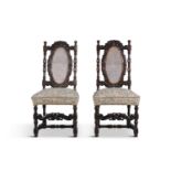 A PAIR OF WALNUT STAINED AND CARVED FRAME SIDE CHAIRS, with oval cane panel backs, the crests with