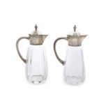 A PAIR OF CONTINENTAL CLEAR GLASS AND SILVER MOUNTED CLARET JUGS, of art deco design with c-scroll