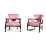 A PAIR OF EDWARDIAN MAHOGANY FRAMED LOW ARMCHAIRS, upholstered in pink silk damask, the arms on