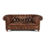 A VICTORIAN BUTTON BACK CHESTERFIELD SOFA, upholstered in close-nailed brown leather, raised on
