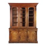 A VICTORIAN THREE DOOR MAHOGANY BOOKCASE, with moulded cavetto cornice, above three clear glazed