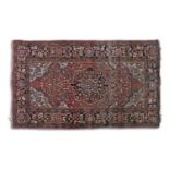 AN ANTIQUE PERSIAN RUG, in red, navy, blue and cream tones, the central reserve containing