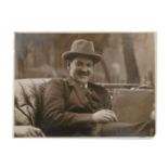 AN ORIGINAL PHOTOGRAPH OF MICHAEL COLLINS, seated in an open car and smiling at the camera,