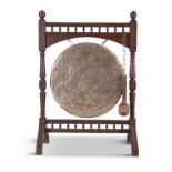 AN OAK AND BEATEN BRASS DINNER GONG, 19th century, the circular panel suspended from a turned oak