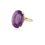 AN AMETHYST RING, the oval mixed-cut amethyst within a four-claw setting, to a plain hoop, mounted