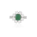 AN EMERALD AND DIAMOND CLUSTER RING The rectangular cut-cornered emerald weighing approximately 1.