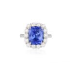 A SAPPHIRE AND DIAMOND CLUSTER RING The cushion-shaped sapphire weighing 5.70cts set in a four-