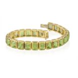 A PERIDOT BRACELET Composed of a line of rectangular-cut peridots within four-claw setting,