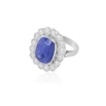 A SAPPHIRE AND DIAMOND CLUSTER RING The cushion-shaped sapphire within collet-setting weighing 7.