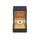 A TOPAZ AND PORCELAIN 'CHANDRA' RING, BY BULGARI, CIRCA 1995 Set with an oval-shaped cabochon blue