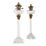 A PAIR OF CUT GLASS OIL LAMPS, in the form of stepped columns, with Corinthian brass capitals and