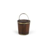 A GEORGE III MAHOGANY BRASS BOUND TURF BUCKET, of coopered construction, with brass swing handle and
