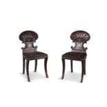A PAIR OF 19TH CENTURY MAHOGANY HALL CHAIRS, with carved scallop shell backs above roundels with