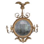 A FINE GEORGE IV GILTWOOD CONVEX GIRANDOLE WALL MIRROR, surmounted by an eagle and scrolls above a