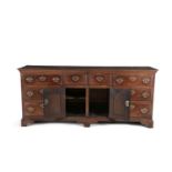 AN 18TH CENTURY OAK WELSH LOW DRESSER, the central section with twin cupboard doors below two