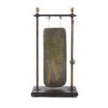 A BRASS AND MAHOGANY FRAMED DINNER GONG, with suspended rectangular brass drum, raised on moulded