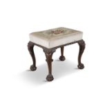 A 19TH CENTURY IRISH CARVED MAHOGANY FOOT STOOL, the embroidered upholstery above a gadrooned rim,