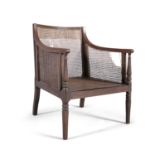 A GEORGE IV MAHOGANY FRAMED BERGERE ARMCHAIR, the reeded frame with fluted arm supports and tapering