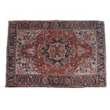 A PERSIAN WOOL CARPET IN THE TABRIZ TASTE, the brick red ground centred with a floral medallion