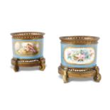 A PAIR OF SEVRES STYLE PORCELAIN CACHE POTS, with ormolu mounts, the cylindrical bodies painted with