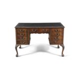 A MAHOGANY AND LEATHER TOPPED WRITING DESK, of rectangular form with central long drawer over arched