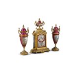 A FRENCH GILT BRASS CASED AND PORCELAIN COMPOSED THREE PIECE CLOCK SET, the clock surmounted with an