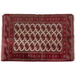 A TURKISH BOKARA PATTERN RED GROUND WOOL RUG, in cream and brick red tones, woven with three rows of