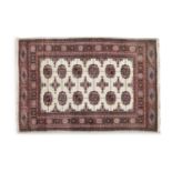 A CREAM GROUND RUG, with central field of oval gul motifs, within pink and brown geometric borders.