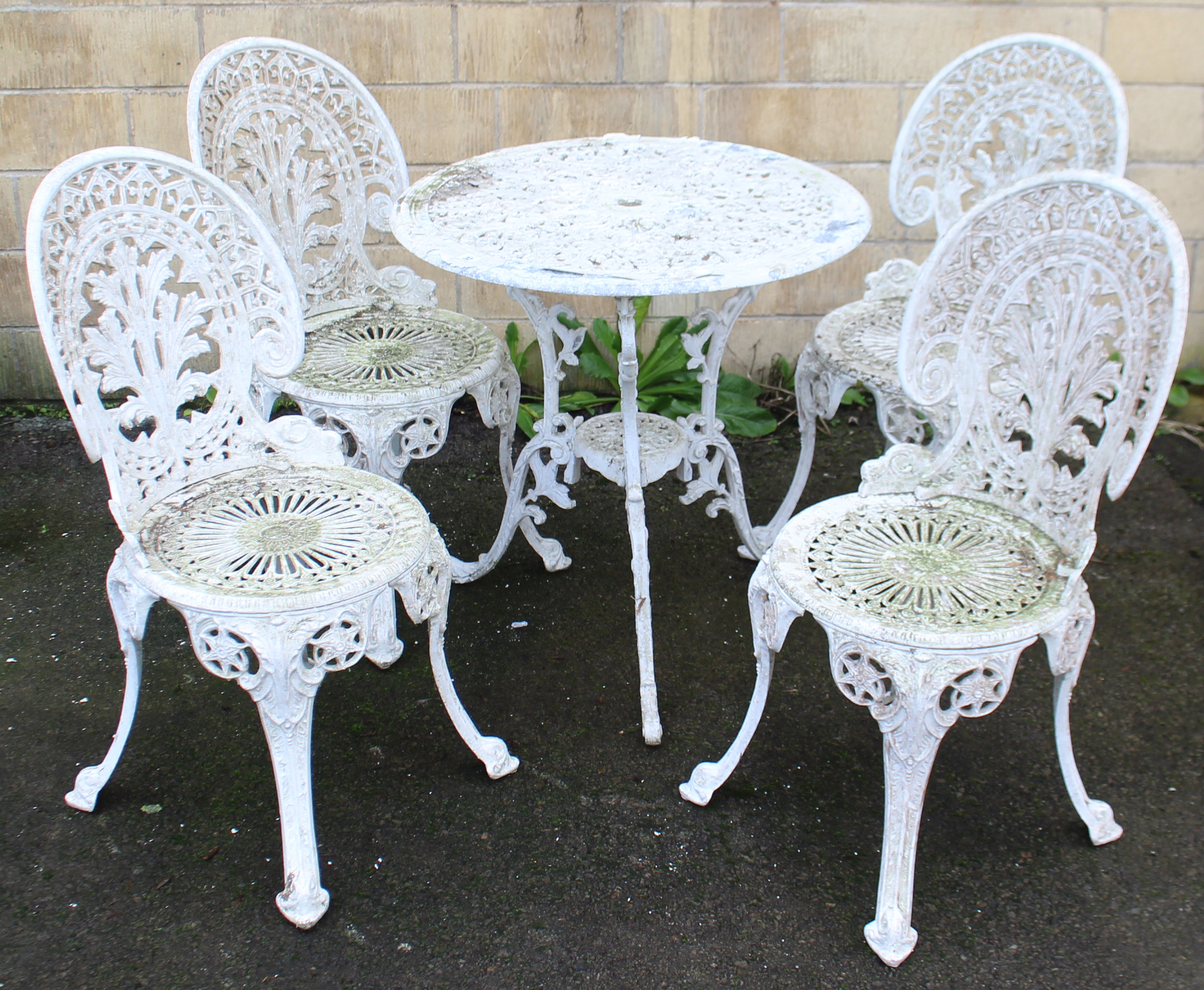 A Victorian-style white painted aluminium patio table with pierced circular top, & on three shaped