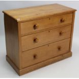 A pine dwarf chest, fitted three long graduated drawers with turned knob handles & on plinth base,
