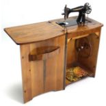 A Singer treadle sewing machine in walnut-finish bow-front cabinet enclosed by panel door, 21¼” wide
