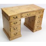 A pine pedestal desk, fitted with an arrangement of nine drawers with brass swan-neck handles, &