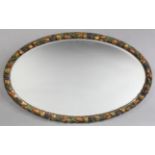 A 20th century oval wall mirror in carved wooden Barbola-type frame; 29” x 18”.