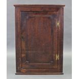 An 18th century oak hanging corner cupboard, with moulded cornice above three shaped shelves,