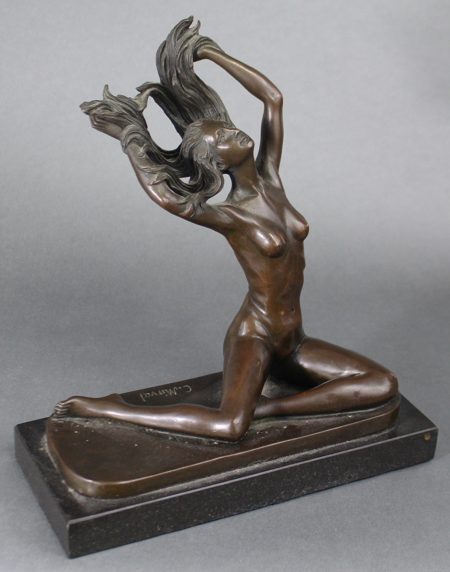 After C. Mirval; a cast bronze female nude figure, seated with hands lifting her flowing hair, on