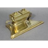 An early 20th century Arts & Crafts gilt brass desk inkstand of shaped rectangular form, the ceramic