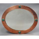 An early 20th century Arts & Crafts oval wall mirror, the rivetted copper frame with planished sur