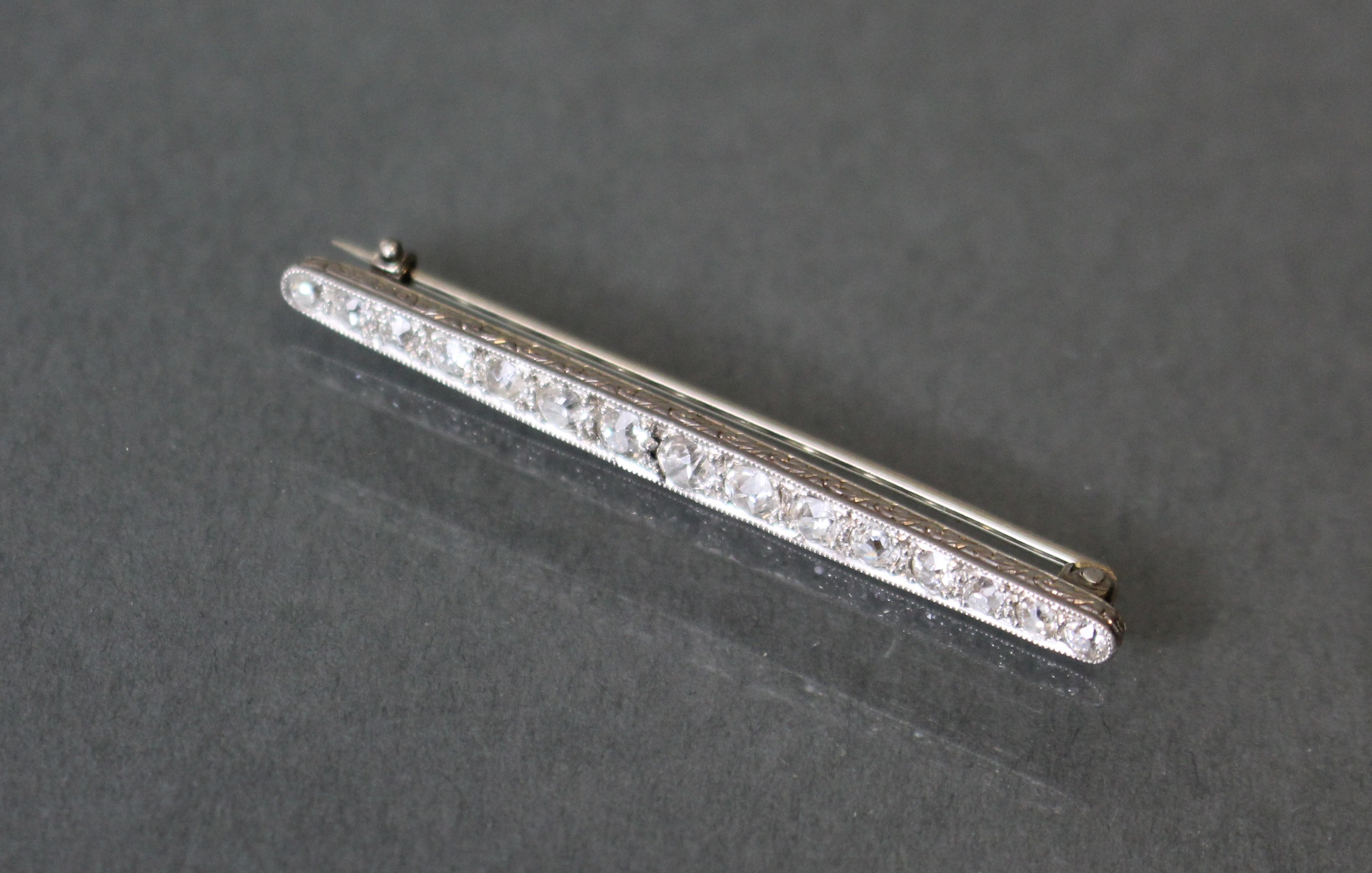 A diamond & platinum bar brooch set fifteen graduated round-cut stones, the narrow sides with - Image 2 of 3