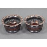 A pair of silver plated wine coasters of pierced cylindrical form, each with flared rim & embossed