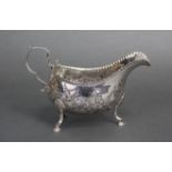 An Irish George III silver oval sauce boat with embossed floral decoration, scroll handle & three