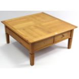 An ash square low coffee table, fitted two frieze drawers to one side, & on short square legs, 39”