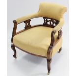 An Edwardian carved beech frame tub-shaped easy chair on short cabriole legs with brass castors; & a