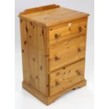 A pine small upright chest, fitted three long graduated drawers with turned knob handles & on shaped
