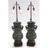 A pair of Chinese-style bronzed ovoid table lamps with ring side handles, complete with shades,