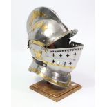 A reproduction silvered-metal medieval knight’s closed helmet, on a wooden stand.